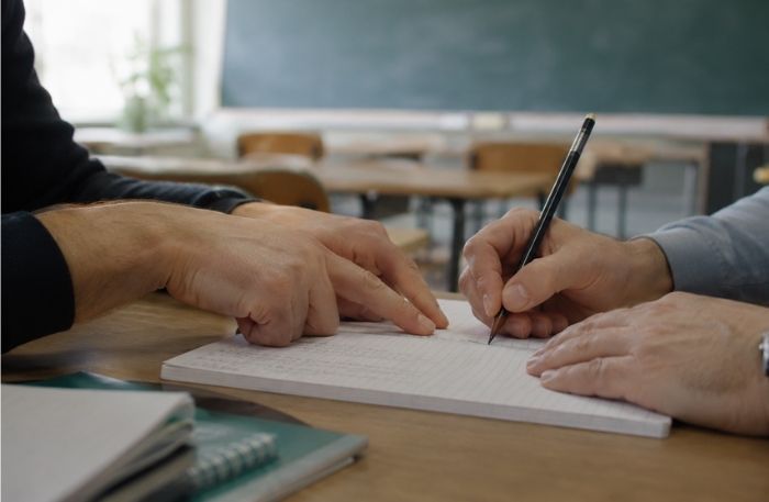 quattro mani che insieme redigono un documento utile per il PDP, ambiente scolastico